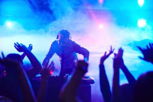 Energetic deejay standing in front of dancing people in club