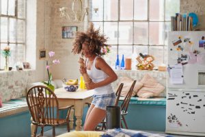 Happy curly haired girl dancing wearing pyjamas at home